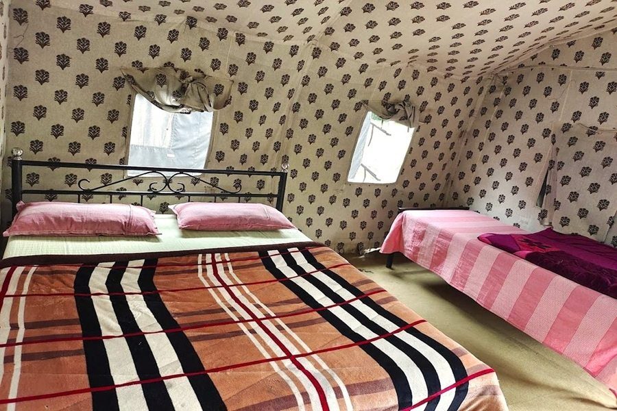 Inside view of a camp tent featuring a double bed and a single bed.