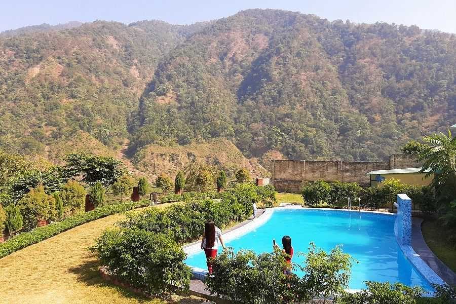 Outdoor swimming pool with clear blue water surrounded by natural scenery.