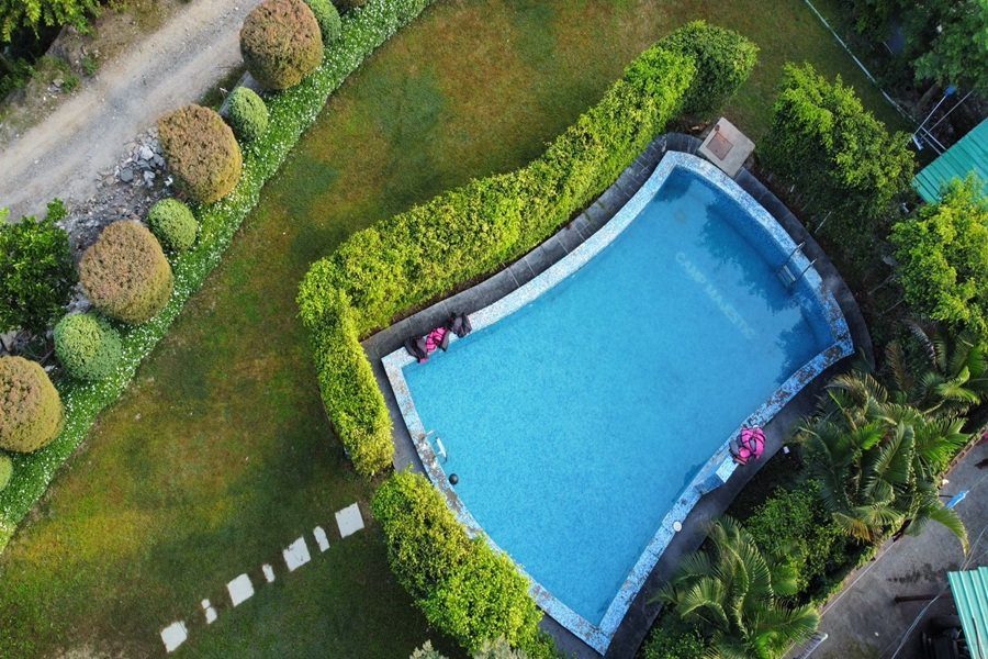 Swimming pool seen from above with clear water and surrounding nature.